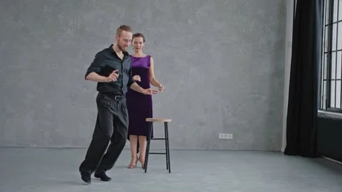 Man showing woman tango elements in grey studio against large windows Vídeo Stock 168629074
