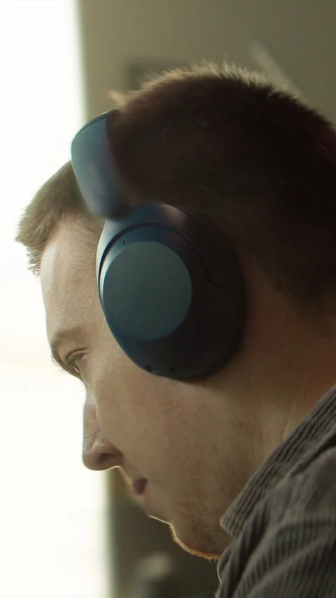 A man is shown in thought, with closeups in a dim room, wearing headphones Stock Footage 319606632
