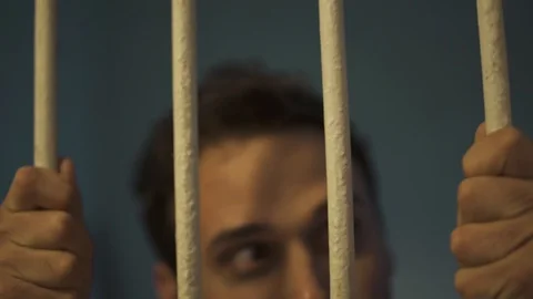 Man shows up behind bar - looking outside his cell Stock Footage 108850032