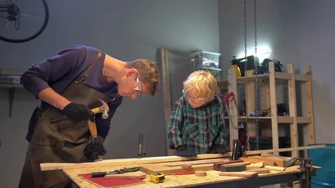 Man shows boy how to work with wood in a workshop Stock Footage 126717216
