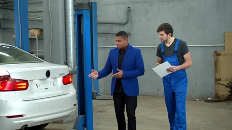 Man shows car damage to mechanic in a car service Stock Footage 124259694
