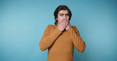 Man shows different expressions of surprise and confusion in front of a blu.. 스톡 동영상 328249984
