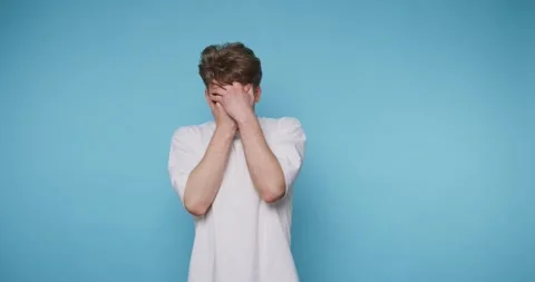 Man shows different reactions using hand gestures against a blue background 스톡 동영상 331990898
