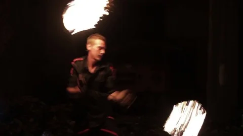 A man shows a fire show in an old aircraft hangar. Stock Footage 79672626