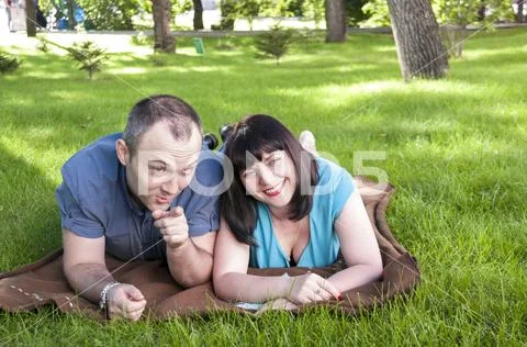 Man shows that the girl away while lying on the lawn Stock Photos