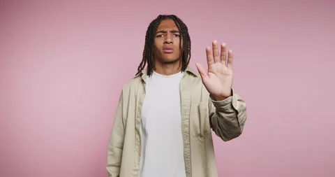 Man shows hand gesture while standing against pink background in casual att.. Stock-Footage 326788031