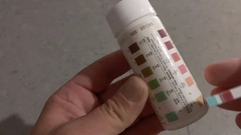 Man shows he is in ketosis with a keto stick and bottle with keto colours Stock Footage