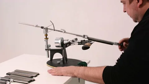 Man shows a master class on sharpening a knife on a machine. Stock Footage 195283302
