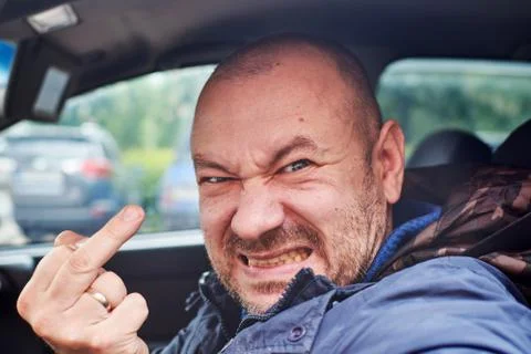 A man shows the middle finger while driving a car. Road aggression, inappropr Stock Photos