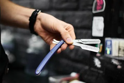 Man shows multitool with scissors and razor in barbershop Stock Photos
