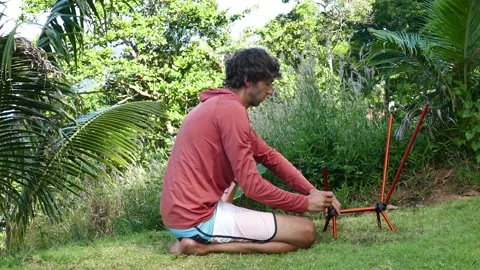 A man shows the process of assembling  a ultralight travel chair in nature Stock Footage 293693534