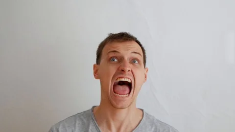 The man shows a quick change of mood on the camera on a white background. The 스톡 동영상 106224203