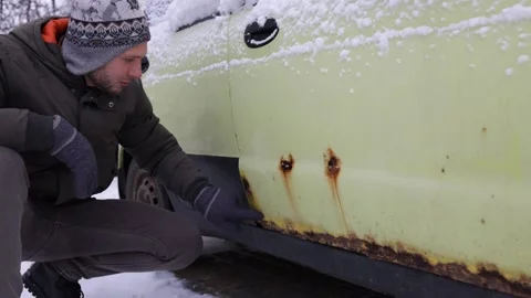 A man shows rust on a car door from winter reagents. Stock Footage 226442537