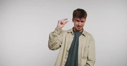 Man shows small size with his fingers in a studio setting during daylight Stock-Footage 326788367