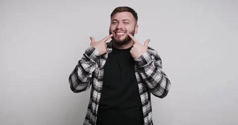 Man shows smile and points at mouth during indoor activity in modern settin.. Vídeo Stock 326798482