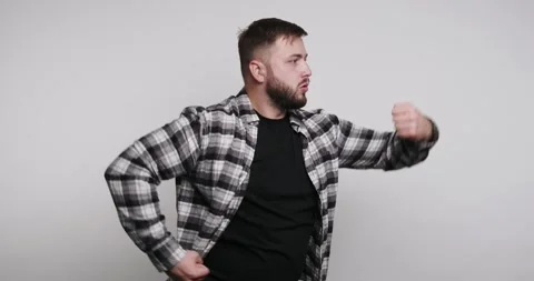 Man shows strength by flexing muscles while wearing a checkered shirt in a .. Stock-Footage 326798429