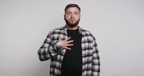 Man shows surprise reaction while standing indoors in front of a plain back.. Stock-Footage 326798275