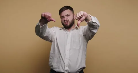 Man shows thumbs down gesture against plain background while expressing dis.. Stock-Footage 326797214