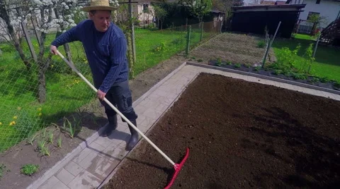 A man shows thumbs up when raking soil in a garden Vídeos de archivo 62524613