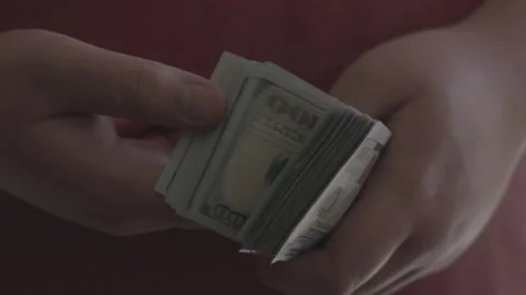 Man shuffling through large stack of $100 USD dollar bills in slow motion Stock Footage 137665126