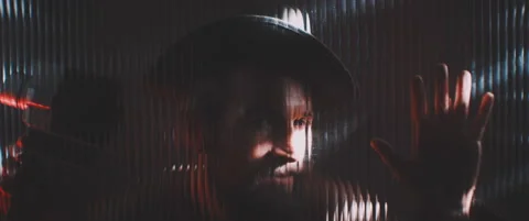 Man in shutter lights looking through clear panel holding hand up Stock Footage 203572084