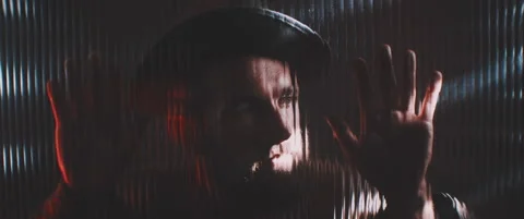 Man in shutter lights looking through clear panel holding hands up Stock Footage 203572439