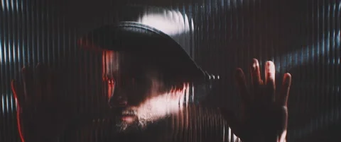Man in shutter lights looking through clear panel holding hands up Stock Footage 203572538