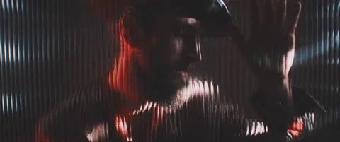 Man in shutter lights looking through clear panel holding hand up Stock Footage 203572776