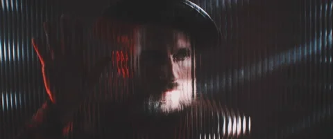 Man in shutter lights looking through clear panel holding hand up Stock Footage 203572951