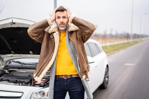 A man by the side of the road is standing in front of a broken car, waiting f Stock-Fotos