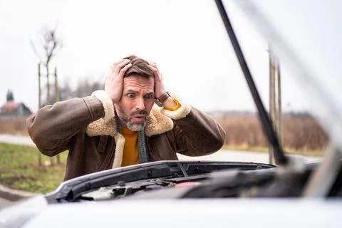 A man by the side of the road is standing in front of a broken car, waiting f Stock-Fotos
