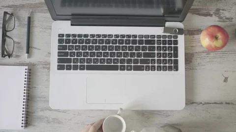 A man sidid behind a laptop and pours coffee Video stock 79441755