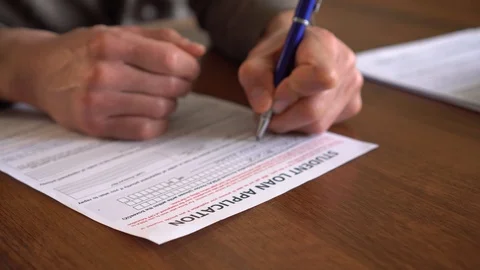 The man signs students loan application paper form document. Student finance Stock Footage 121899859