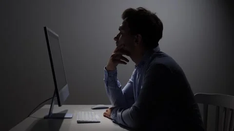 Man in silhouette concentrating while working late on a desktop computer Stock Footage 342672318