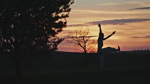 Man silhouette practices yoga in evening against sunset. Silhouette of man Stock Footage 201385210