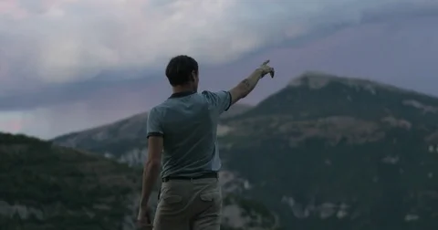 Man silhouette stands back on mountain top showing pointing finger 4k close up Stock Footage 79982763
