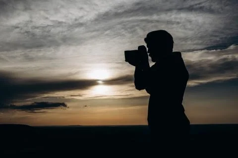 Man in silhouette using camera for making photos of sunset Foto stock