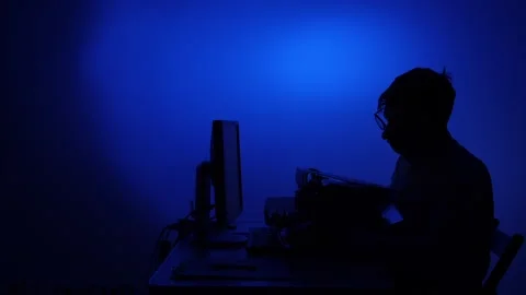 Man silhouette working on computer with blue light Stock Footage 318979747