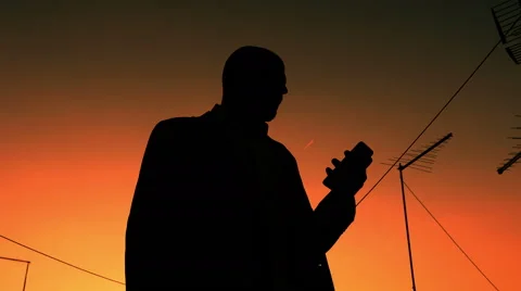 Man silhouetted in the sunset nervous because waiting for a call Video stock 69022703