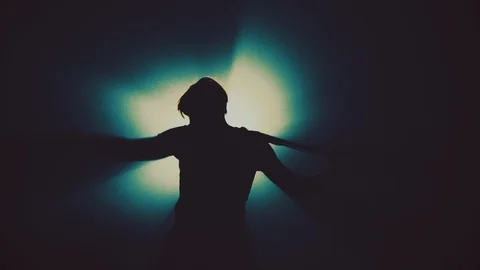 Man singer in the smoke and light sings into a microphone and dance. Dark Stock Footage 105604032