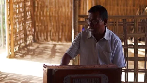 Man singing while playing harmonium inside a traditional rural home Stockbeeldmateriaal 340022920