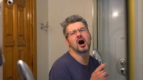 A man sings in the bathroom in front of the mirror 4K Video stock 127720184