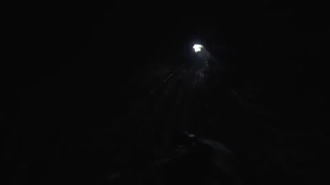 Man in a sinkhole looking at distant entry light. Видео 333291441