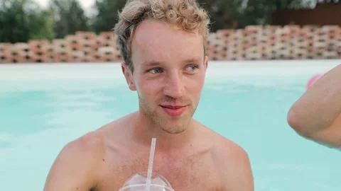 Man is sipping juice. Smiling guy drinking non alcoholic cocktail in pool Stock Footage 149606400