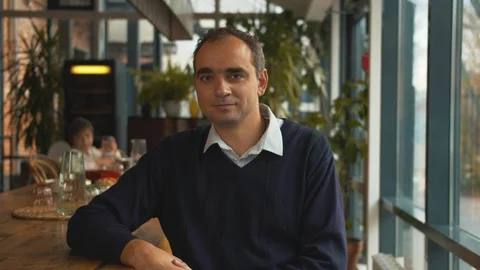 Man sit on chair in a cafe and look at camera with smile Stock Footage 120802013