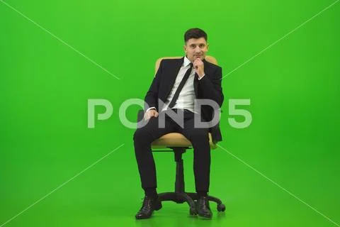 The man sit of the chair on the green background Stock Photos