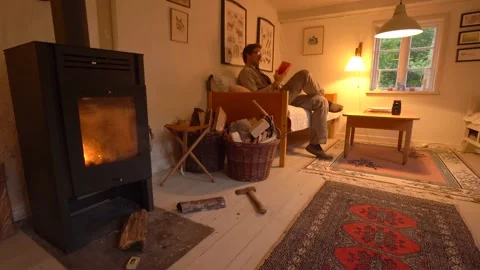 Man Sit On The Couch And Read Book Near The Fireplace Of A Tiny House. - Stock Footage 202802949