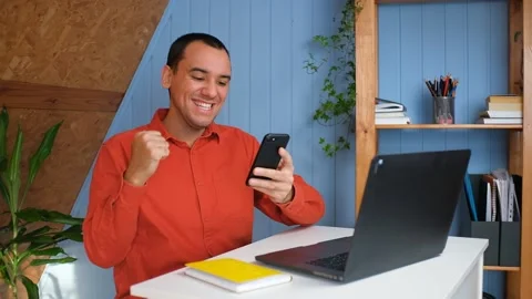 Man sit at desk read message on smart phone feels excited incredible happy Stock Footage 148228157