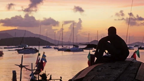 Man sit down beach looks out to sea as amazing sunset on beautiful beach with 스톡 동영상 82291348
