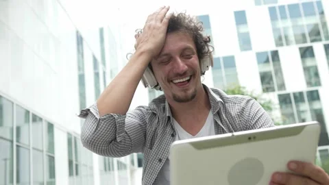 Man sit in front of building use digital tablet to watch movie podcast Stock Footage 248085856